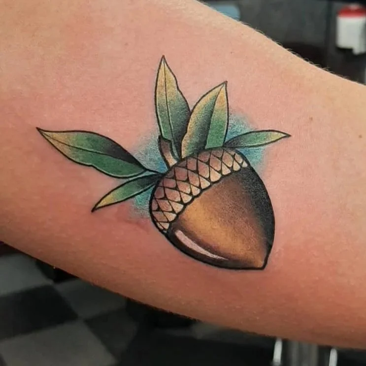 Neo-traditional acorn tattoo with detailed leaves and soft shading
