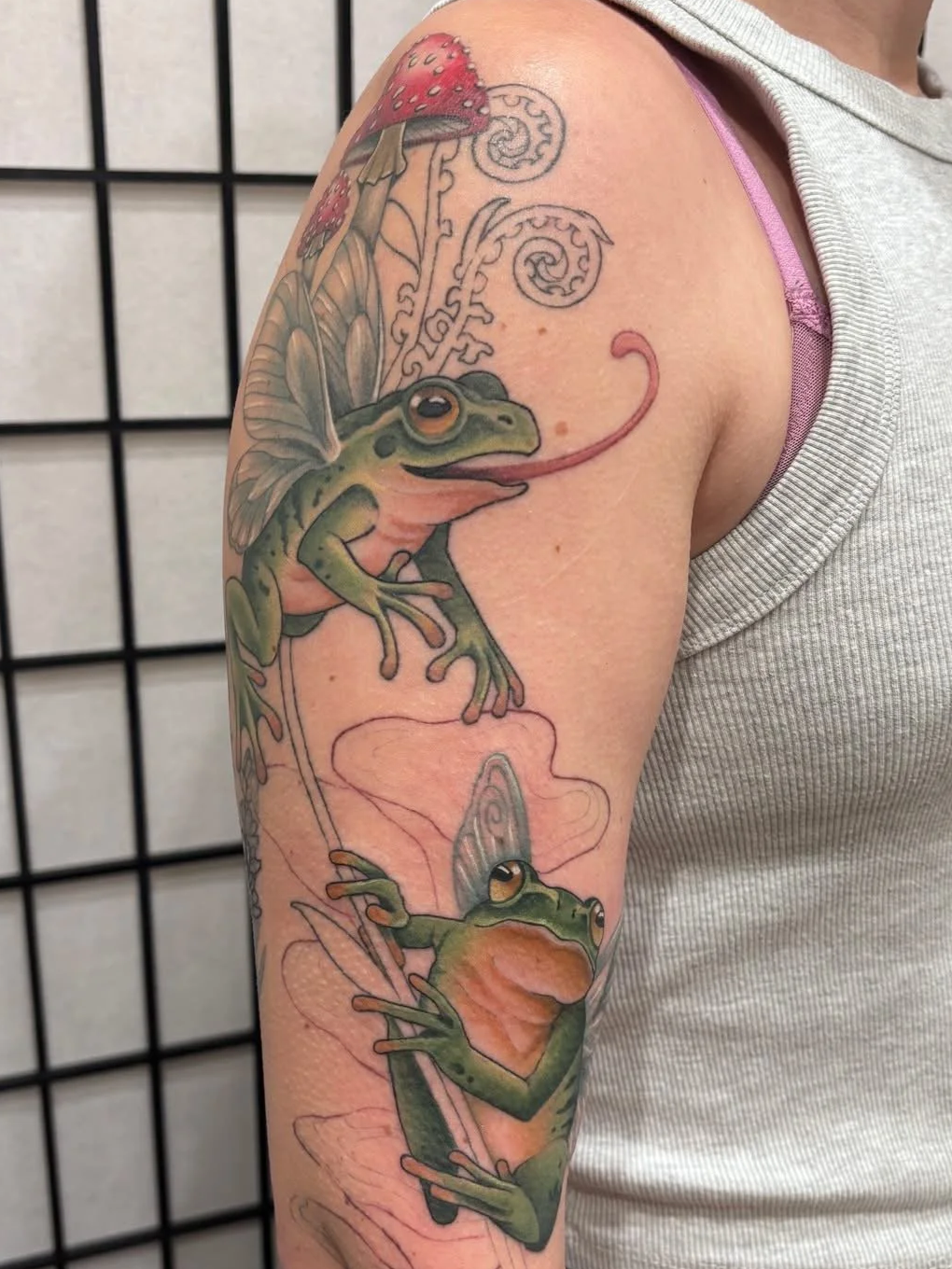 Whimsical fairy frog tattoo with mushrooms, delicate wings, and playful neo-traditional detail