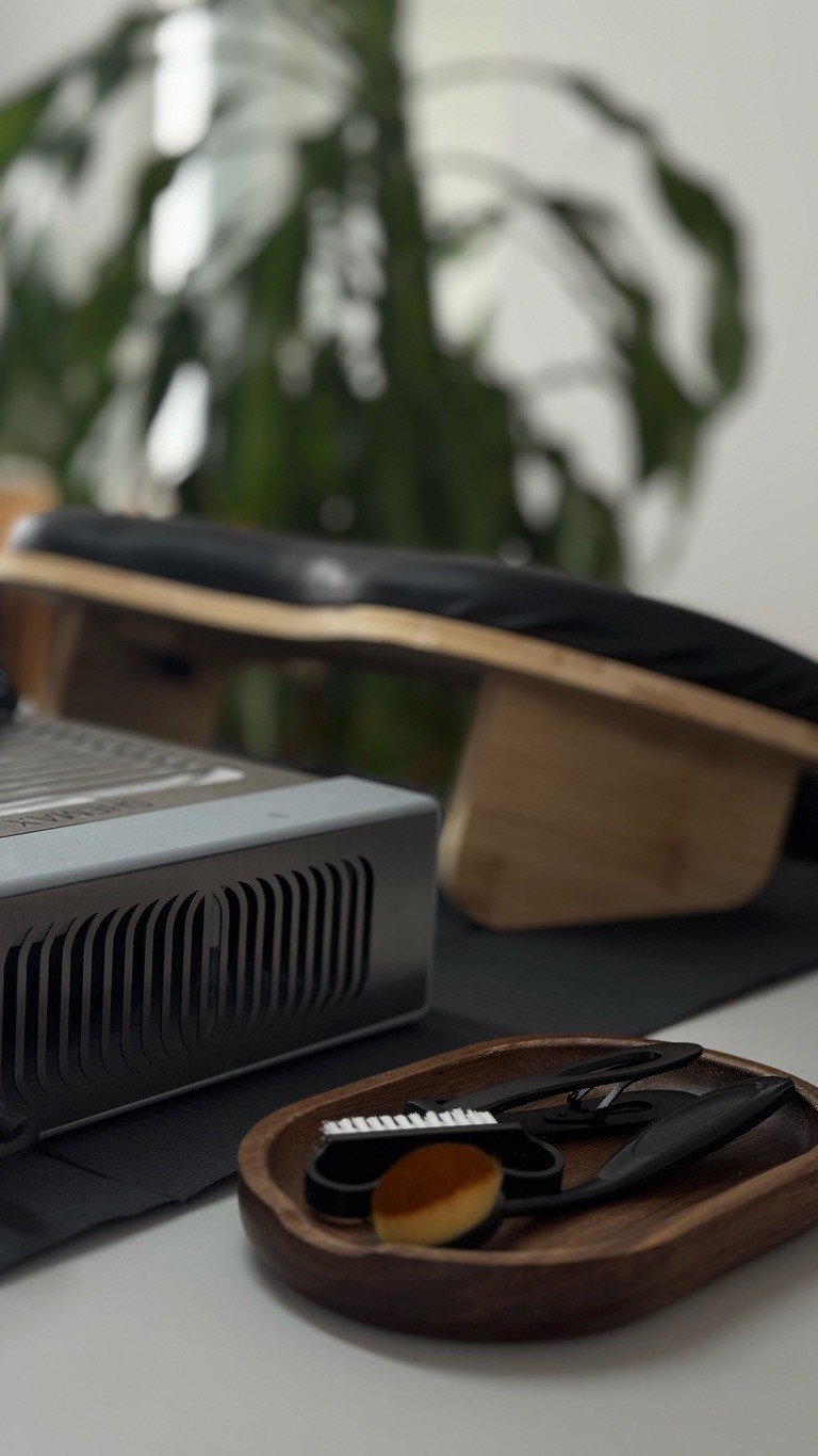 Un espace de bureau avec un projecteur, une petite assiette en bois contenant des ciseaux, un coupe-ongles, un coupe-pédicure et une brosse à ongles, une plante verte en arrière-plan.