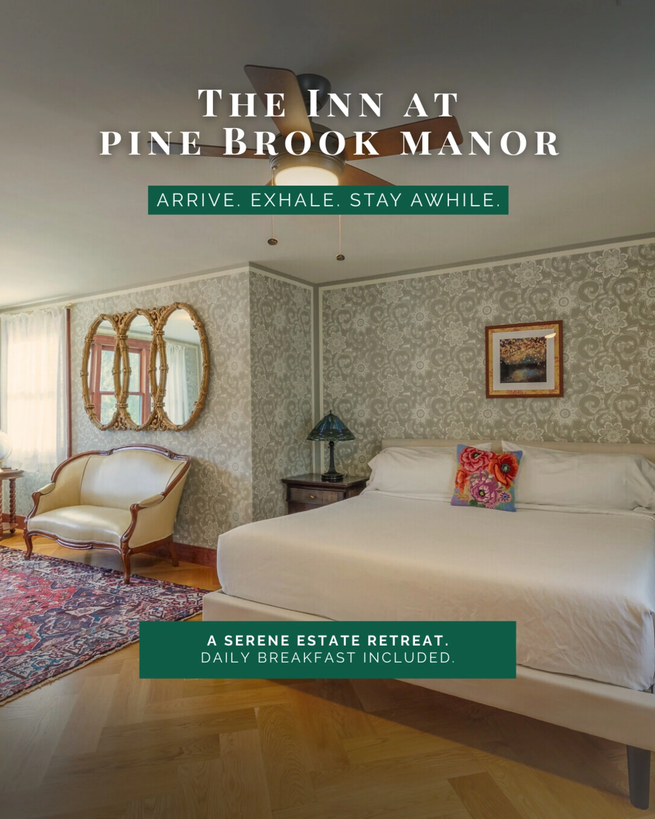 Interior of a cozy bedroom with patterned wallpaper, a beige bed with a colorful throw pillow, a vintage armchair, a mirror, a window with curtains, a framed picture, a table lamp, a ceiling fan, and a patterned rug.