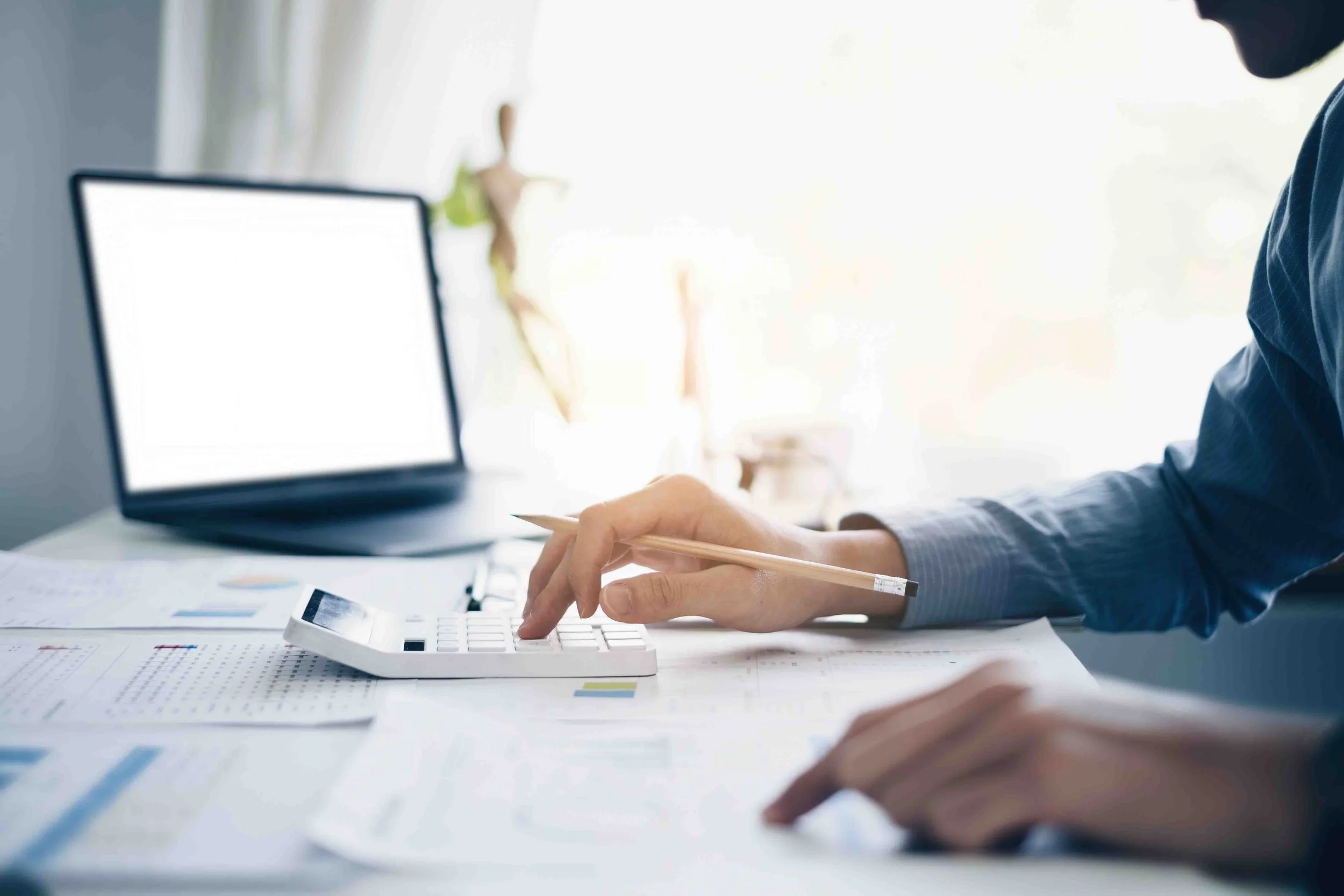 Woman working on laptop while preparing tax and accounting documents