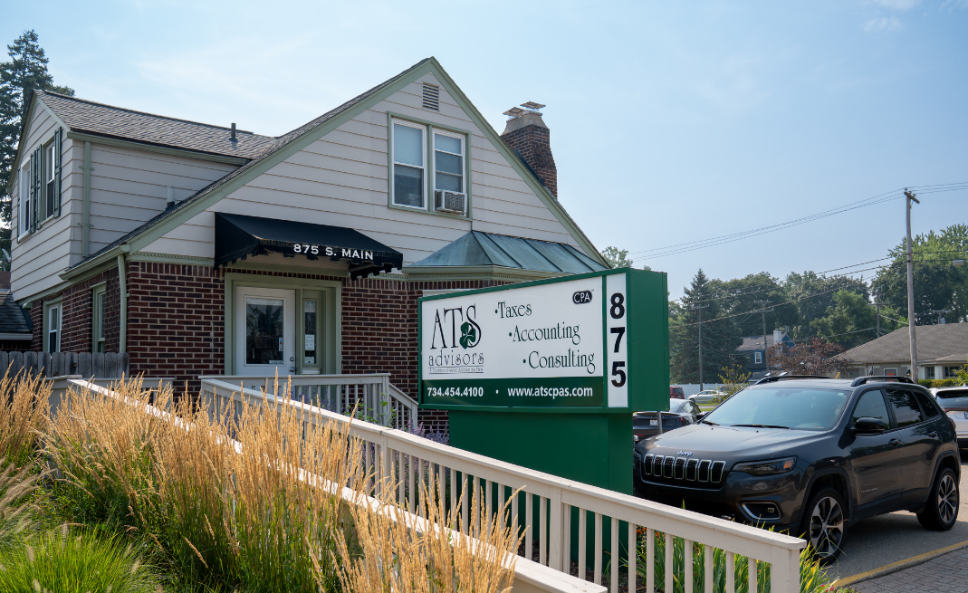 Exterior view of a two-story building with a sign advertising ATCS Advisors, an accounting and consulting firm, and a black SUV parked in front.