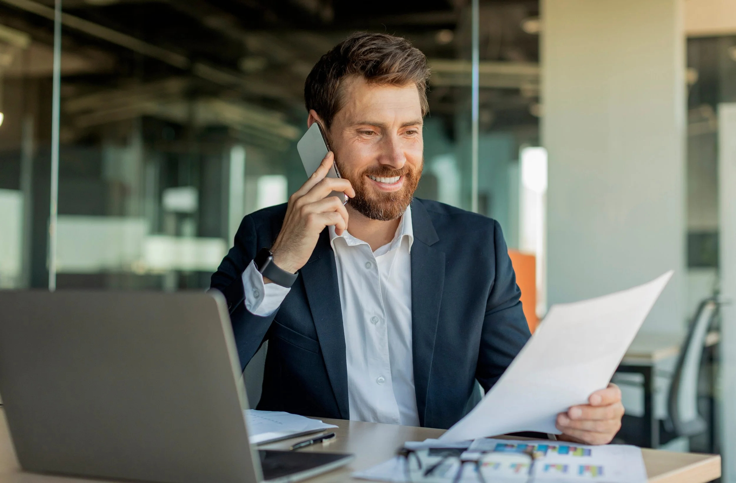 Man on phone reviewing tax documents and financial statements in office