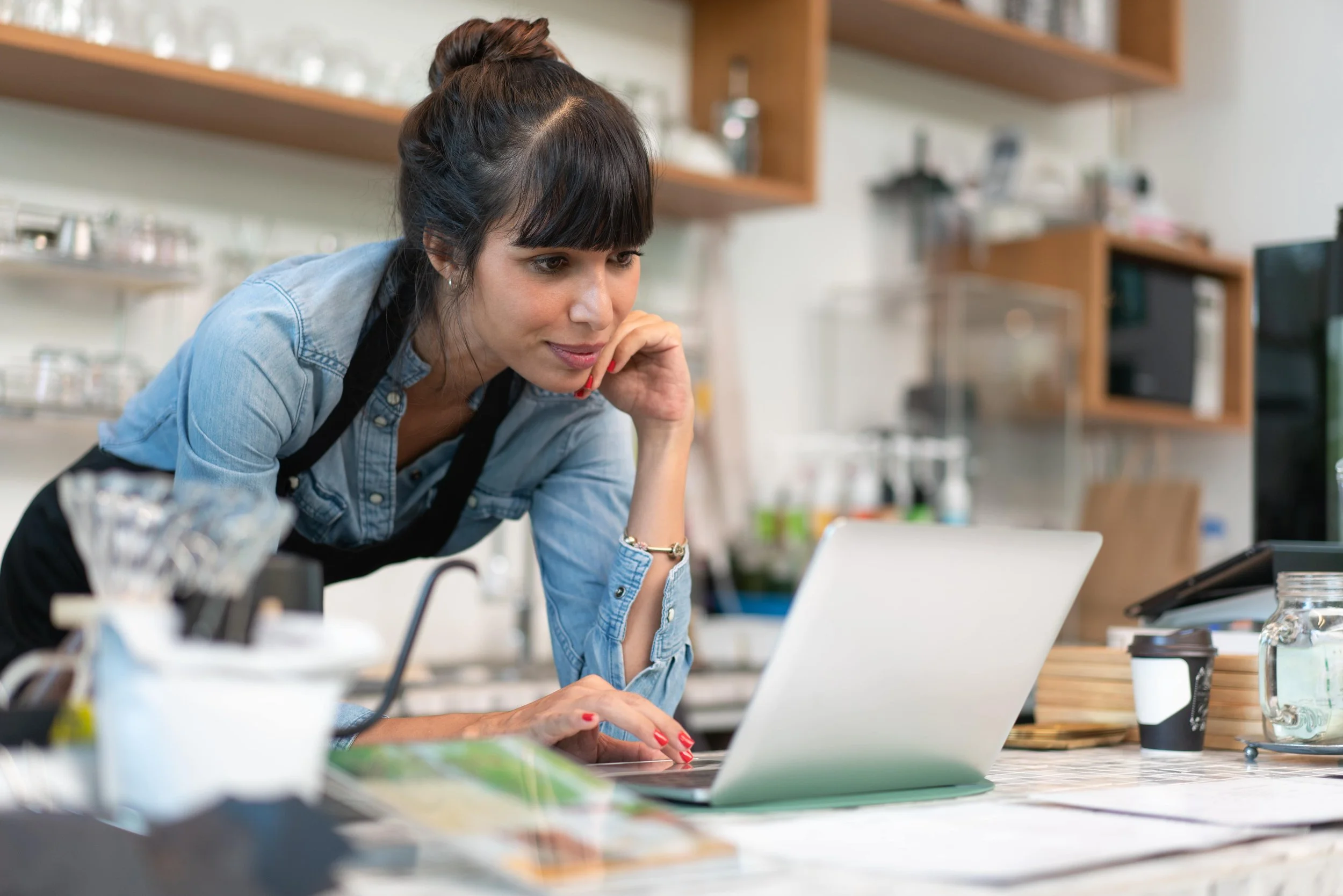 Woman working on laptop while reviewing bookkeeping and accounting records
