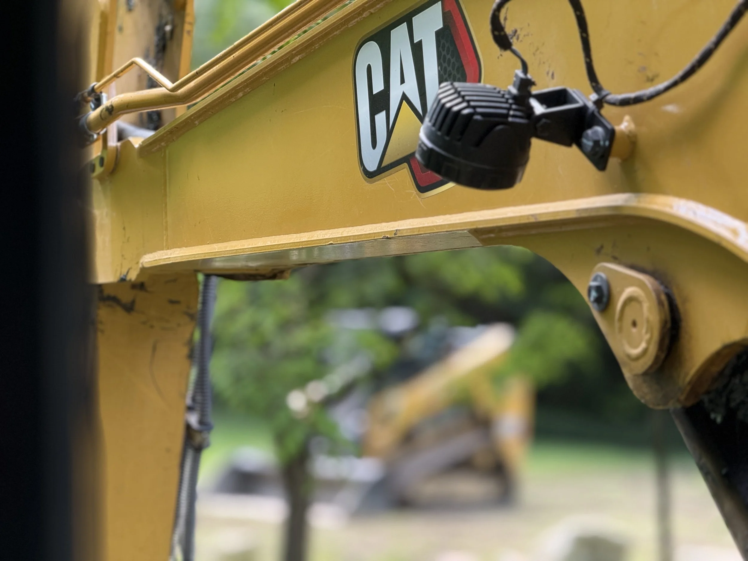 Close-up of a yellow Caterpillar construction vehicle with a visible Caterpillar logo, electrical components, and wiring.