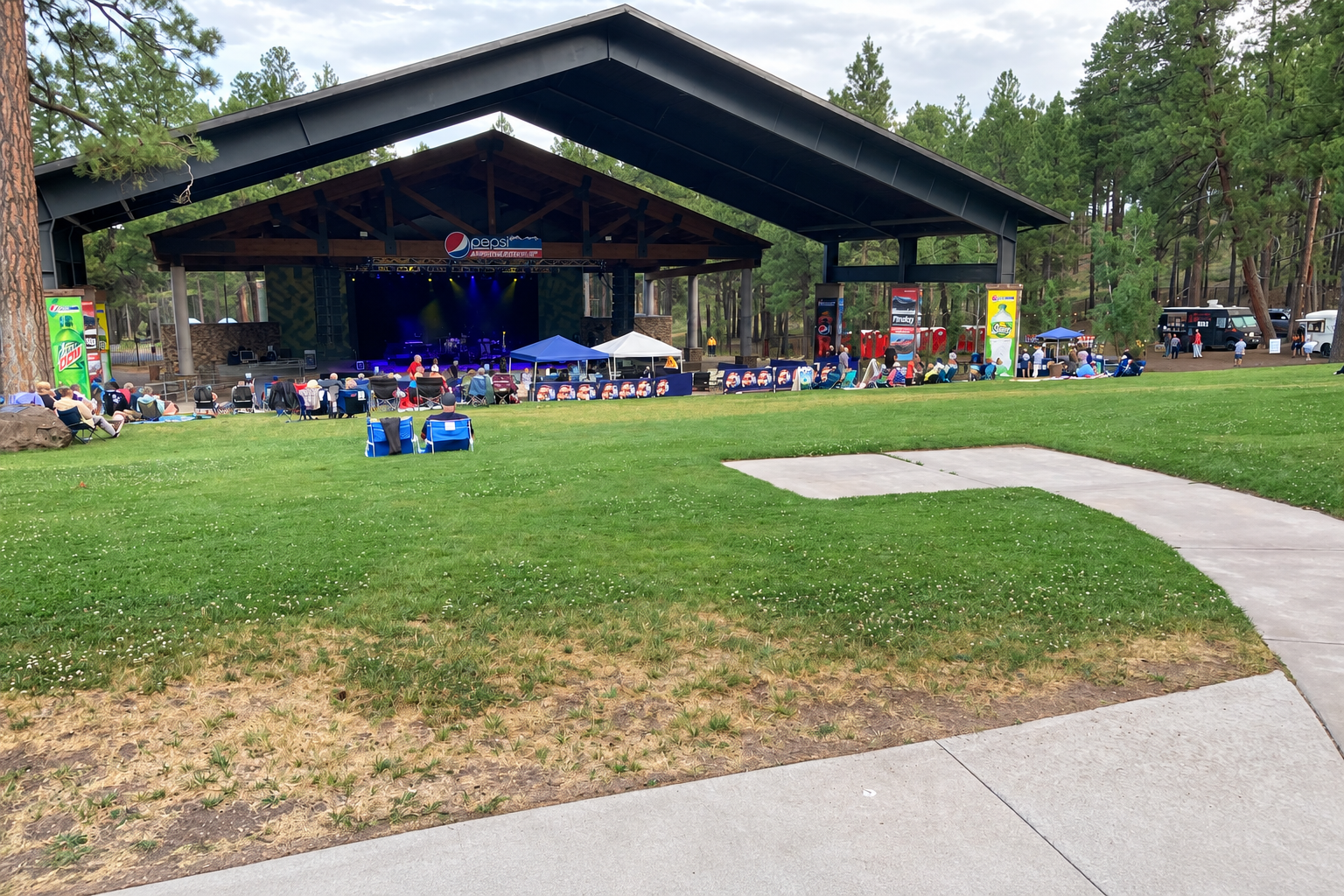 PepsiCo Amphitheater in Flagstaff, with concertgoers on the lawn beneath ponderosa pines.