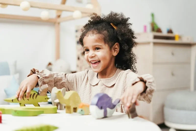 child playing with wooden animals smiling