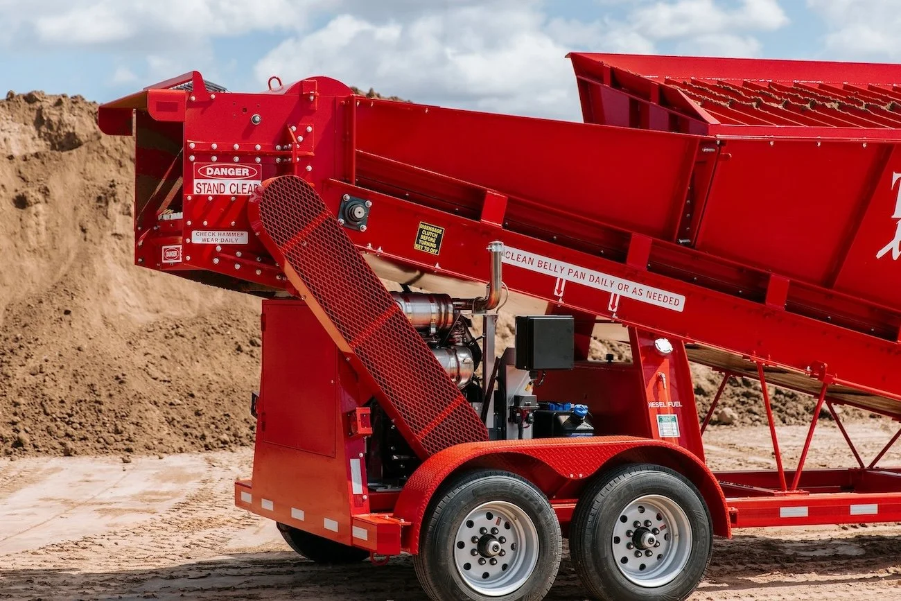 Red mobile equipment with wheels in a construction or excavation site, with dirt and soil in the background.