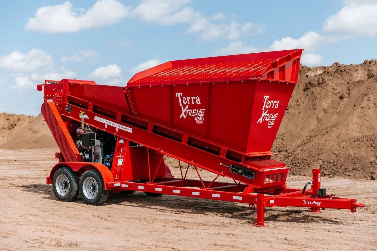 Red Terra Xtreme 4240 dump trailer on a construction site with dirt piles and partly cloudy sky.