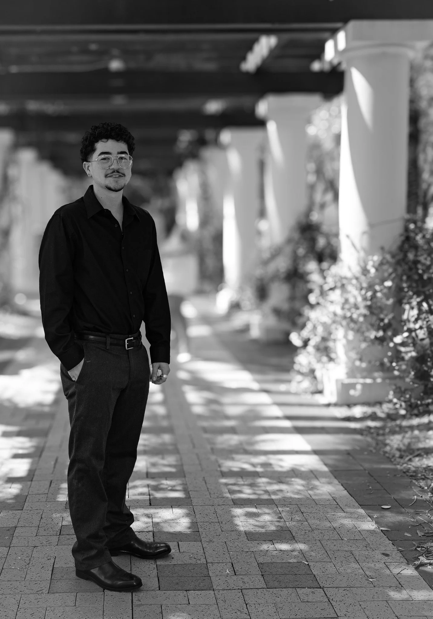 Black and white portrait of a boy standing by columns with a strong perspective view