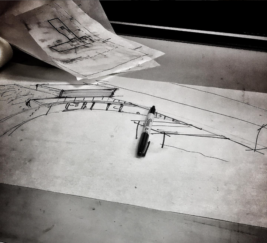 Modern architectural sketches and blueprints on paper with a black marker on a table.
