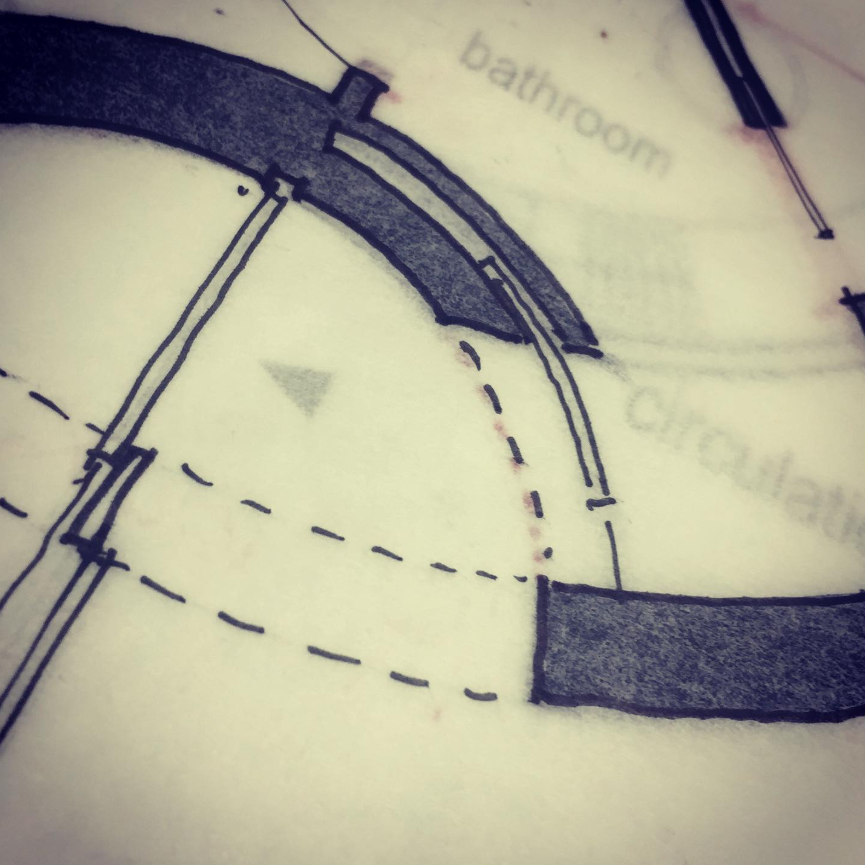 Close-up of a plan showing a curved pocket door drawn with black ink on tracing paper.