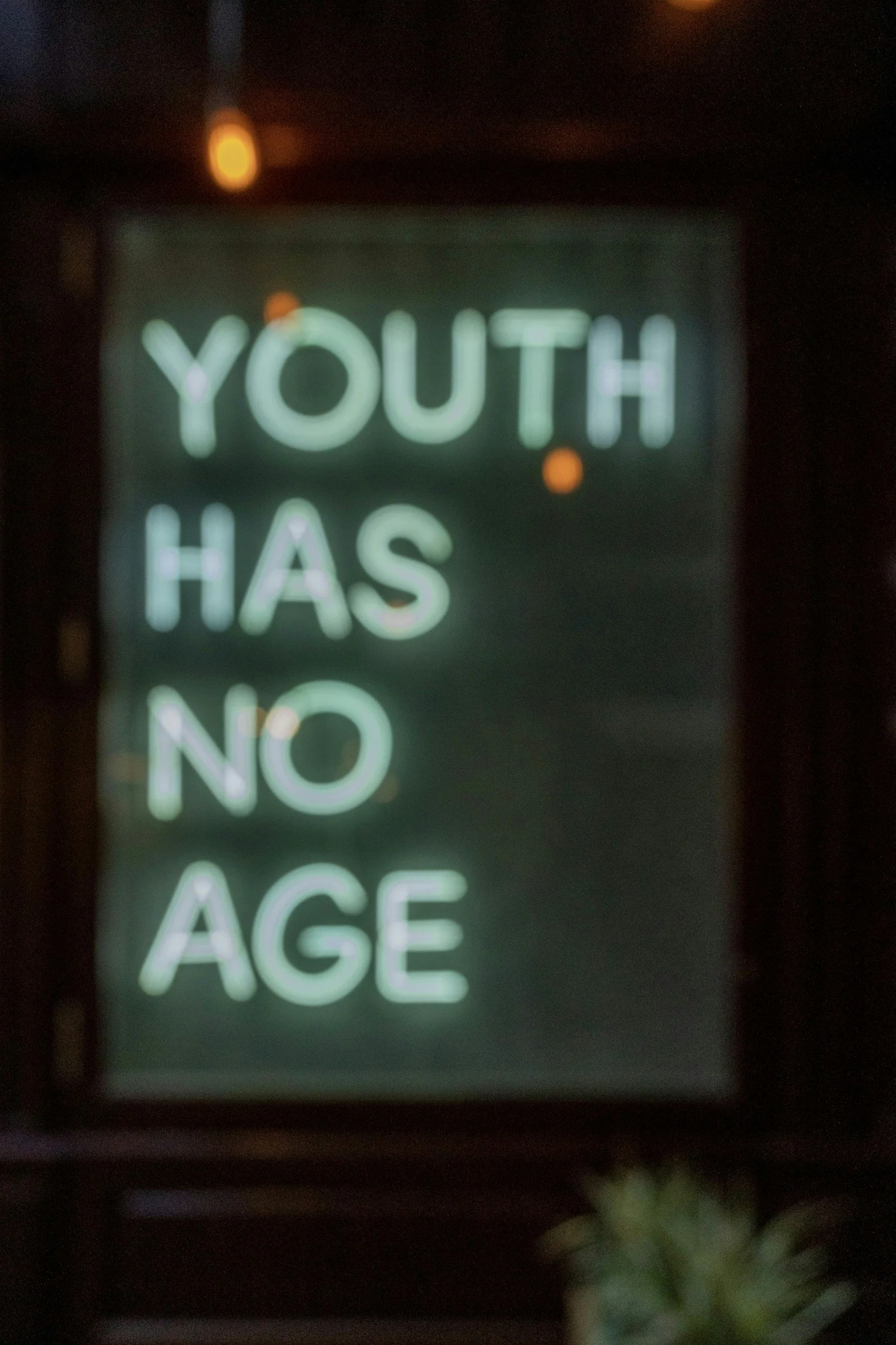 Neon sign reading 'YOUTH HAS NO AGE' in green.