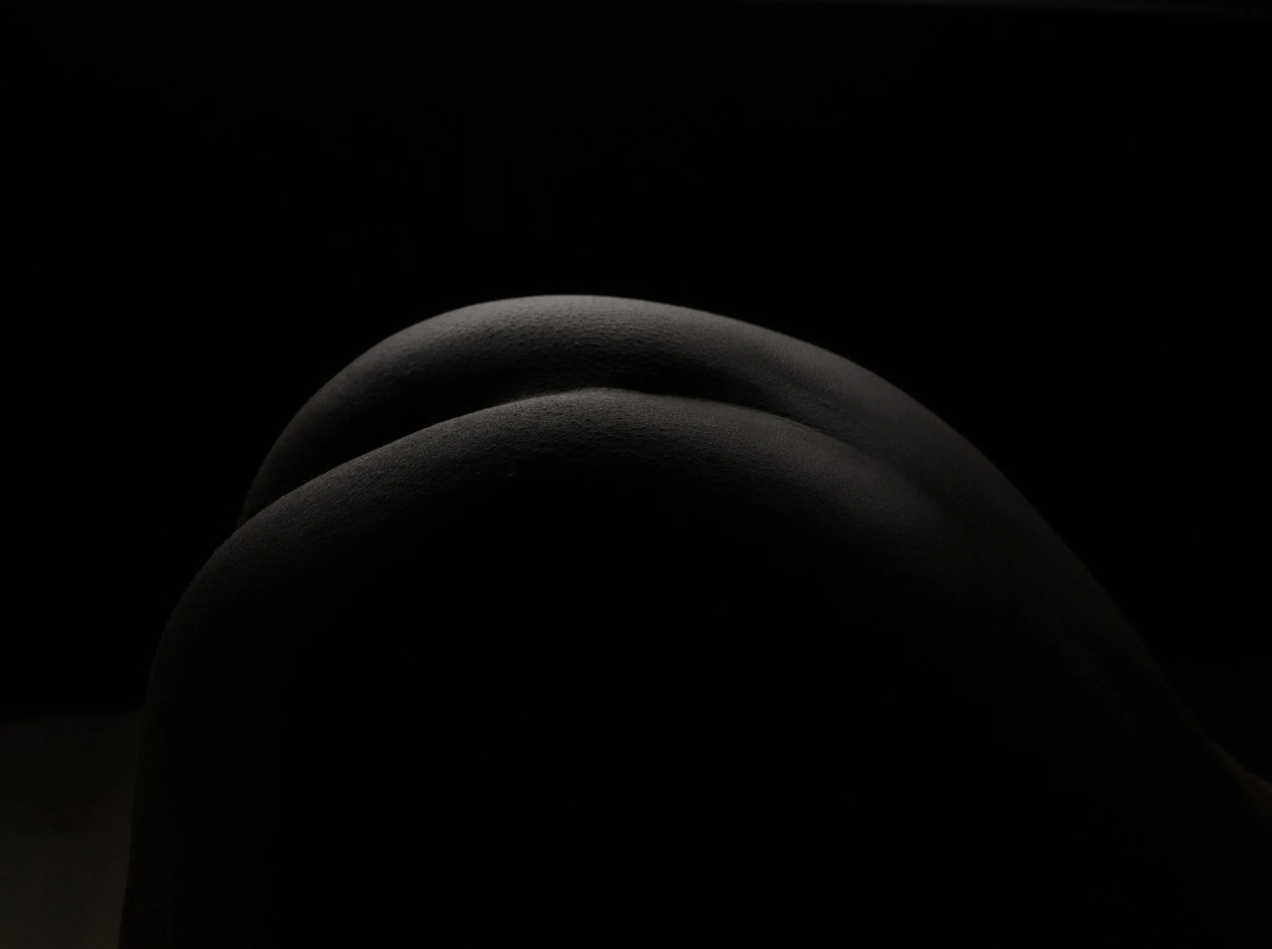 Close-up of a person's knees with a dark background, lit subtly from the side.