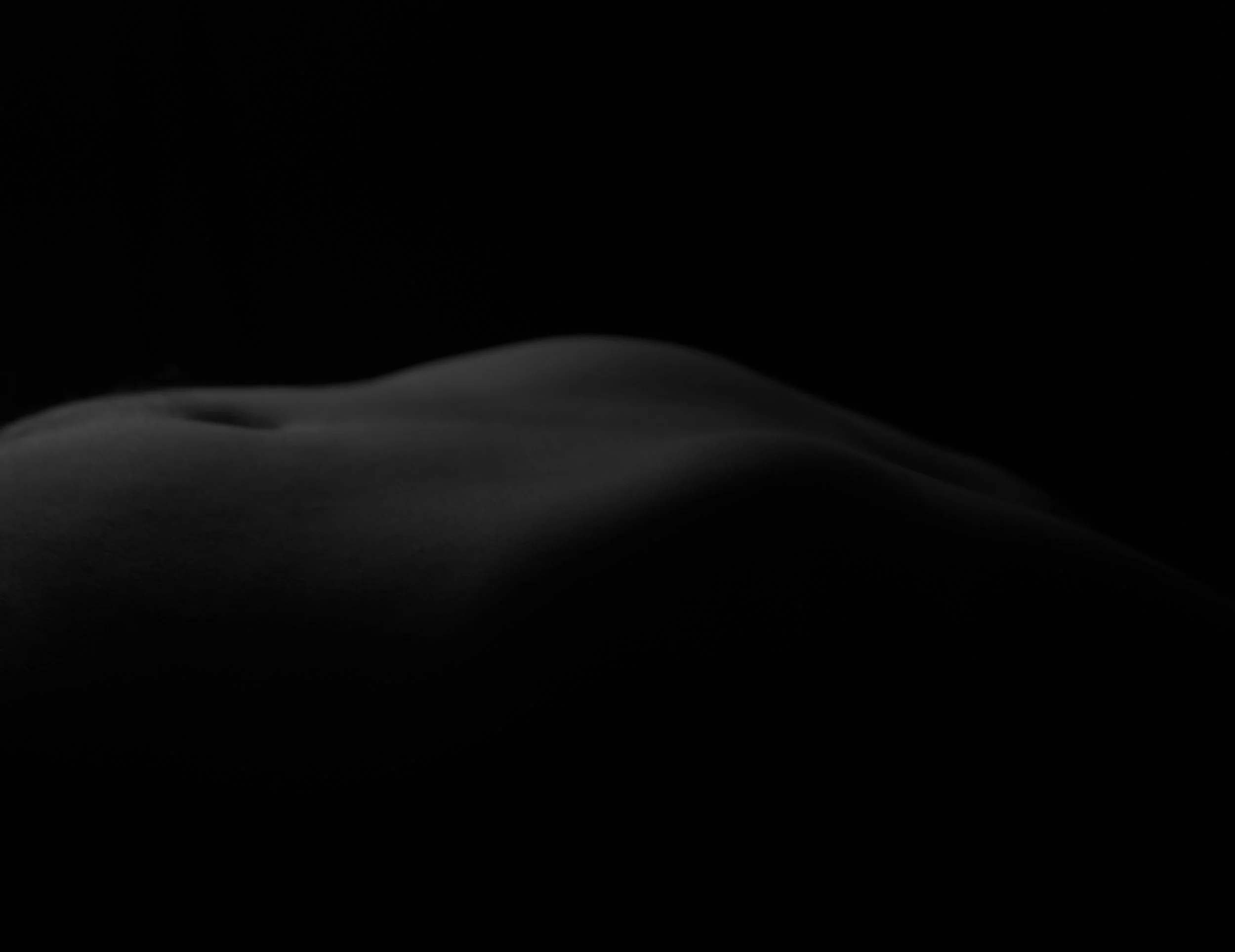 Close-up of a human hand against a black background, showing only part of the hand with smooth lighting.
