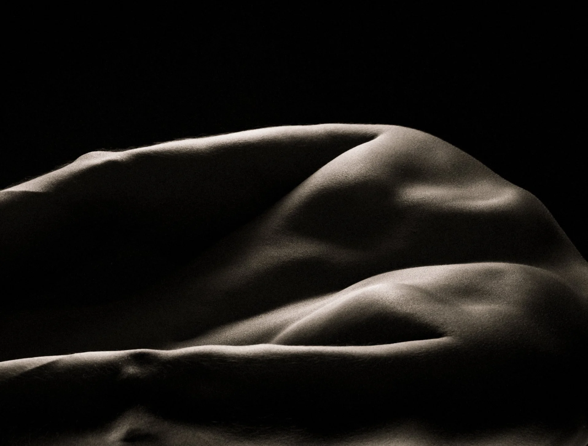 Bodyscape, Fine Art Photography.  Close-up of smooth, flowing, light-colored fabric against a black background.