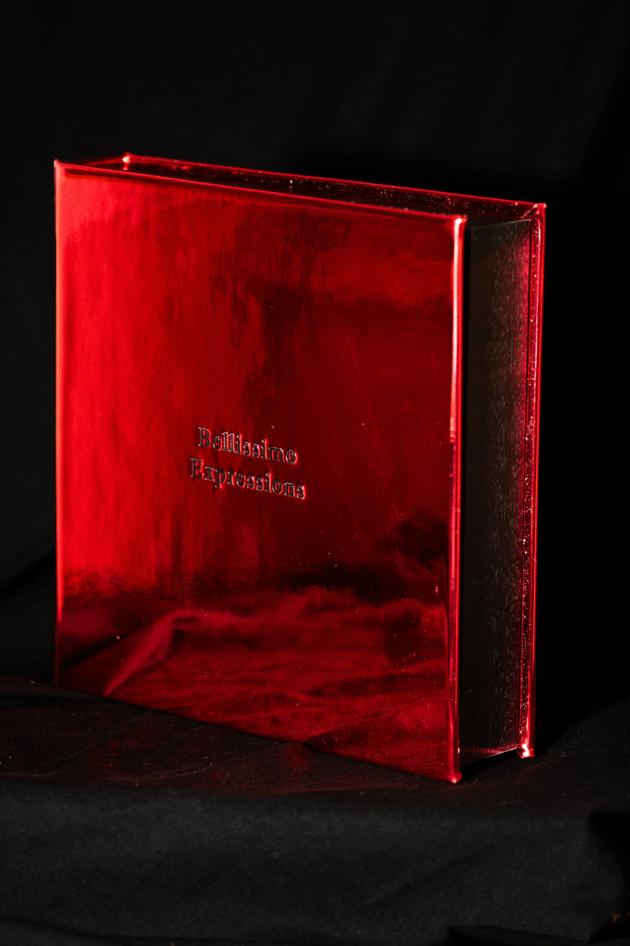 A photo box with the words 'Bellissimo Expressions' engraved on it, placed against a black background.