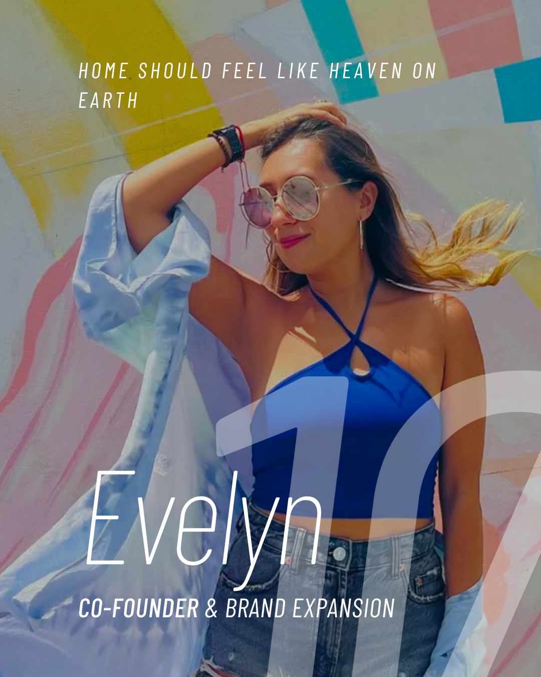 A young woman with sunglasses and earrings, wearing a blue halter top and high-waisted denim shorts, standing against a colorful abstract mural background.