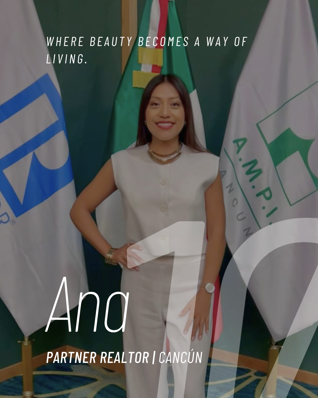 A woman in a white suit standing in front of flags, smiling at the camera.