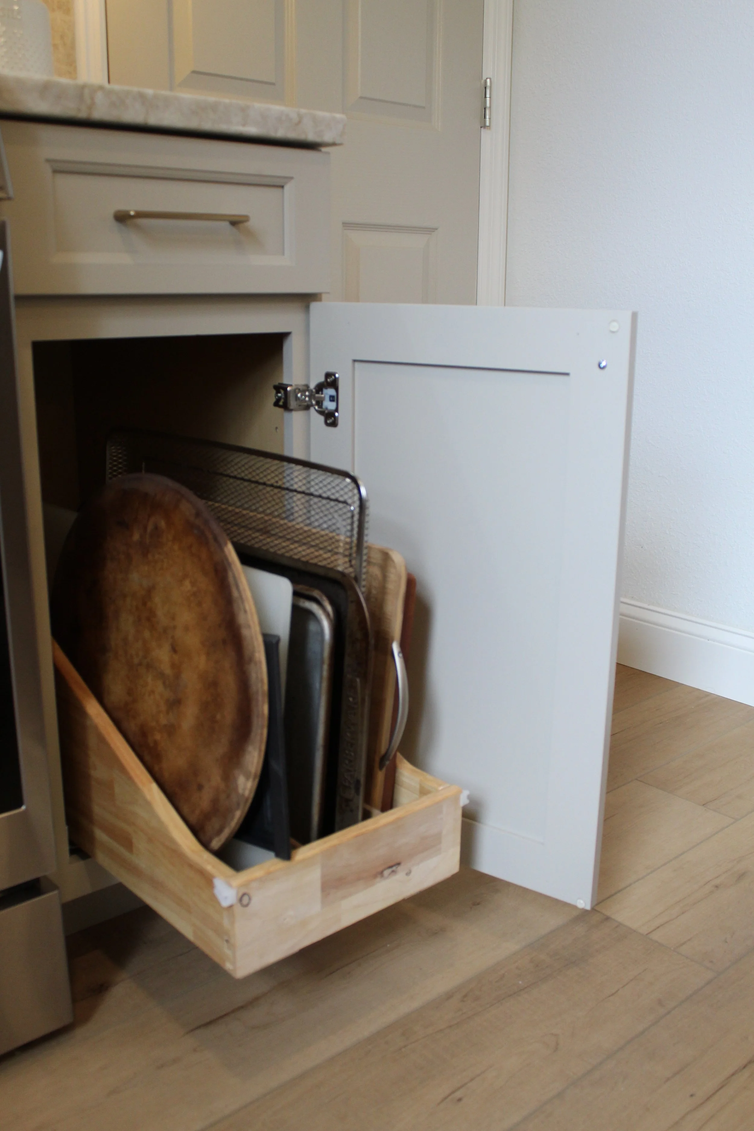 Open kitchen cabinet drawer containing cutting boards, a wire rack, and other kitchen items.