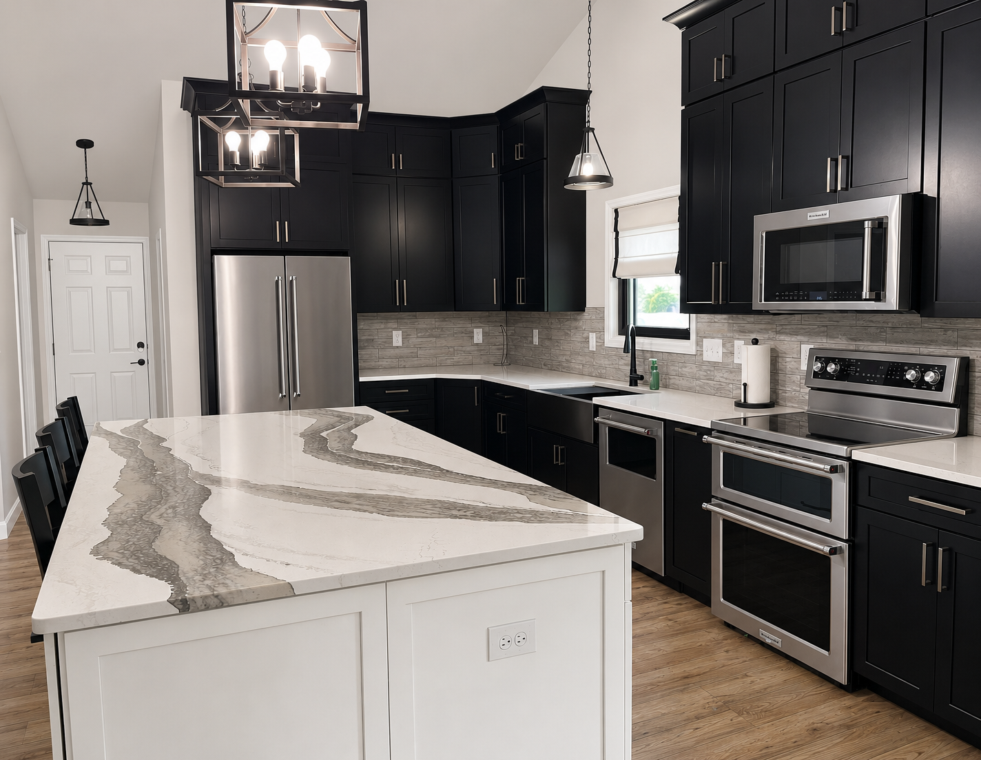 Modern kitchen with black cabinets, stainless steel appliances, and a large white island with gray veining.