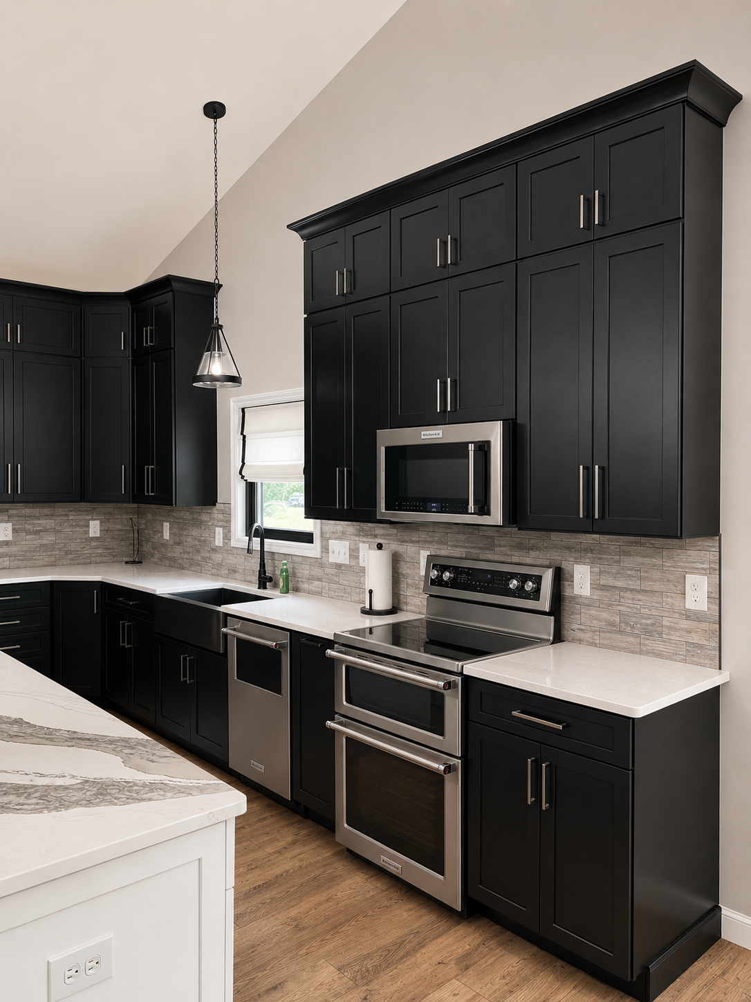 Modern kitchen with black cabinetry, white countertops, stainless steel appliances, and a beige brick backsplash.