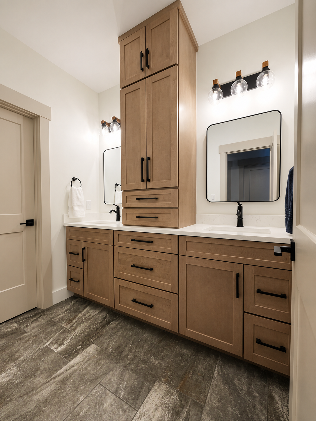 Bathroom with wooden cabinets, white countertop, two mirrors, black faucets, and modern lighting fixtures.