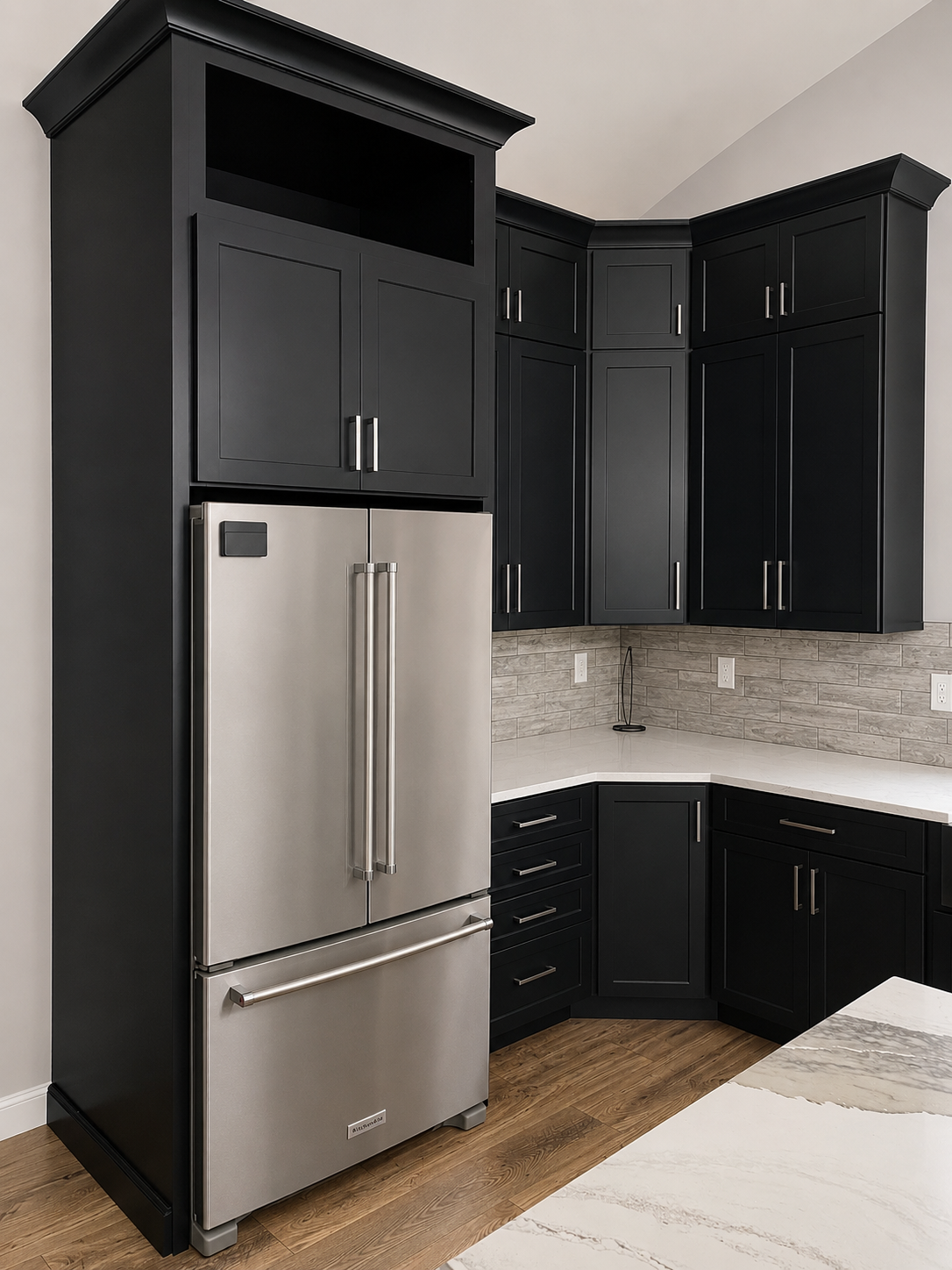 Kitchen corner with black cabinets, stainless steel refrigerator, beige tile backsplash, wooden floor, and white quartz countertops.