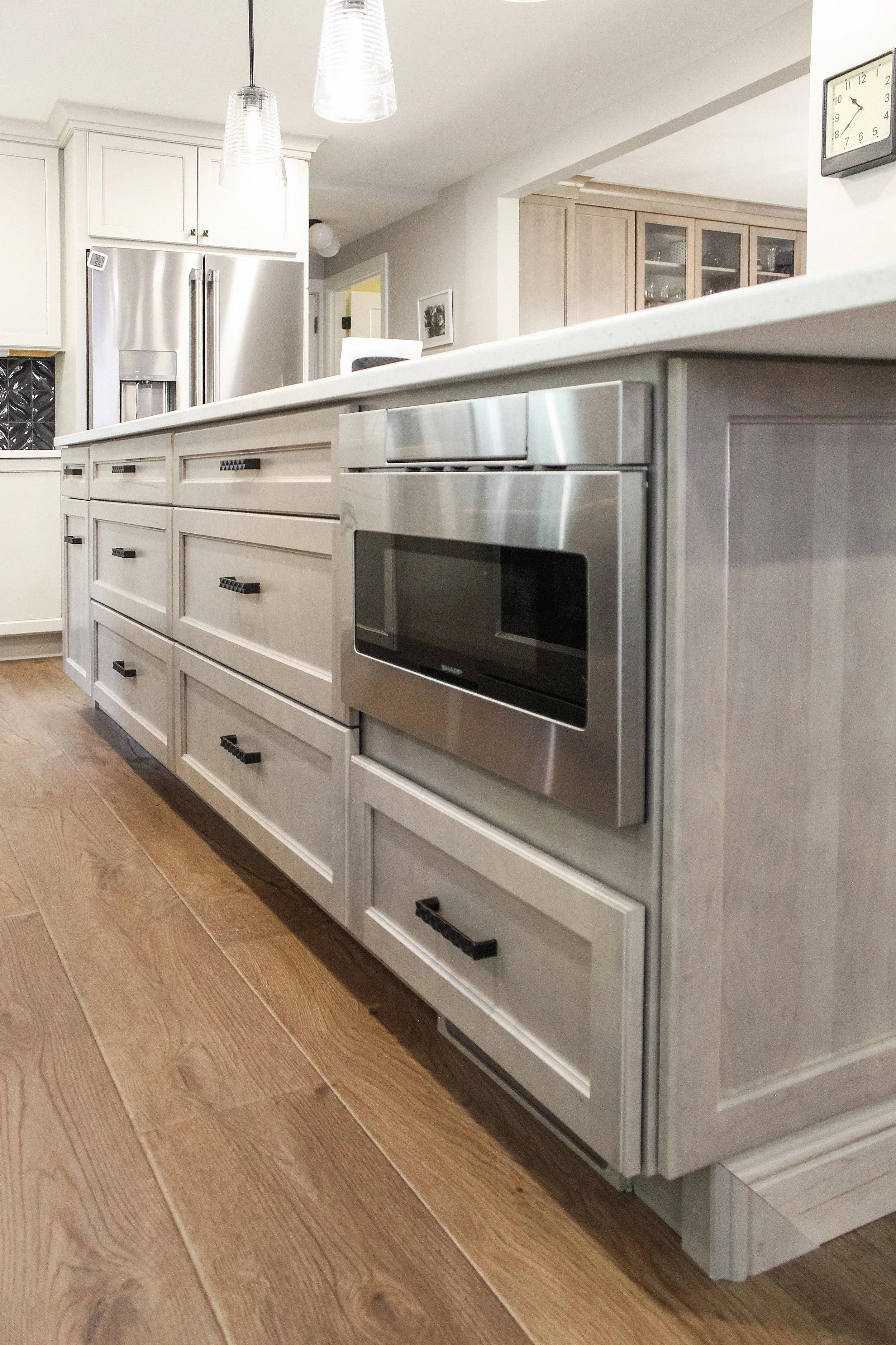 Modern kitchen with white cabinetry, stainless steel appliances, and wood flooring.