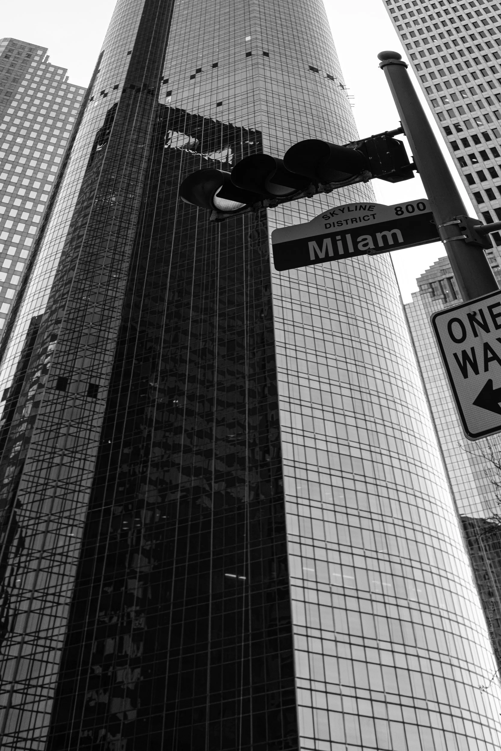 The Milam sign against a curved glass tower.