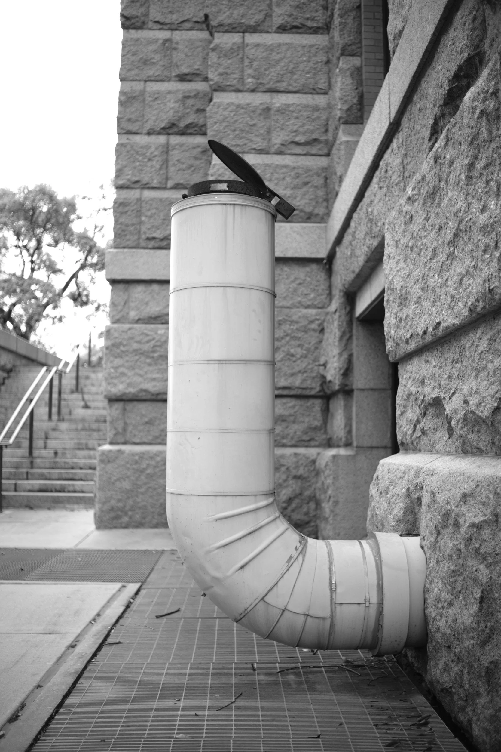 A vent pipe bending out of a granite wall.
