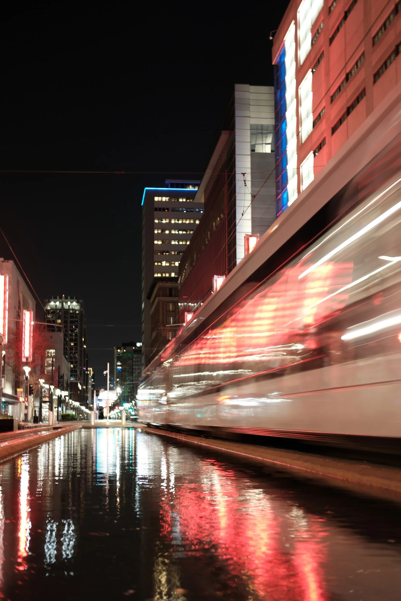 A METRORail train smears its lights across a wet Main Street.