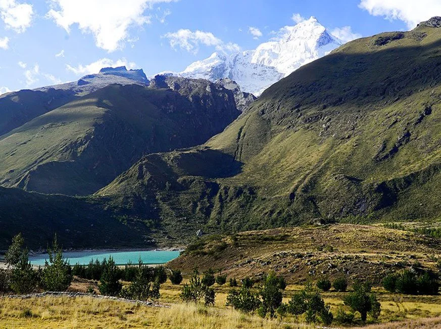 Paisaje con montañas verdes, un lago de agua azul y nieve en las cimas de las montañas en el fondo