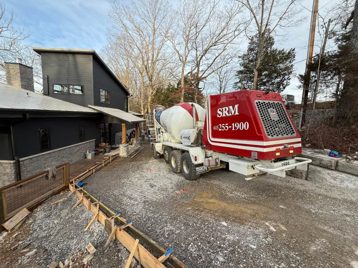 Concrete mixer truck backed up to the job site with wooden forms set along the edges, ready for the driveway pour.