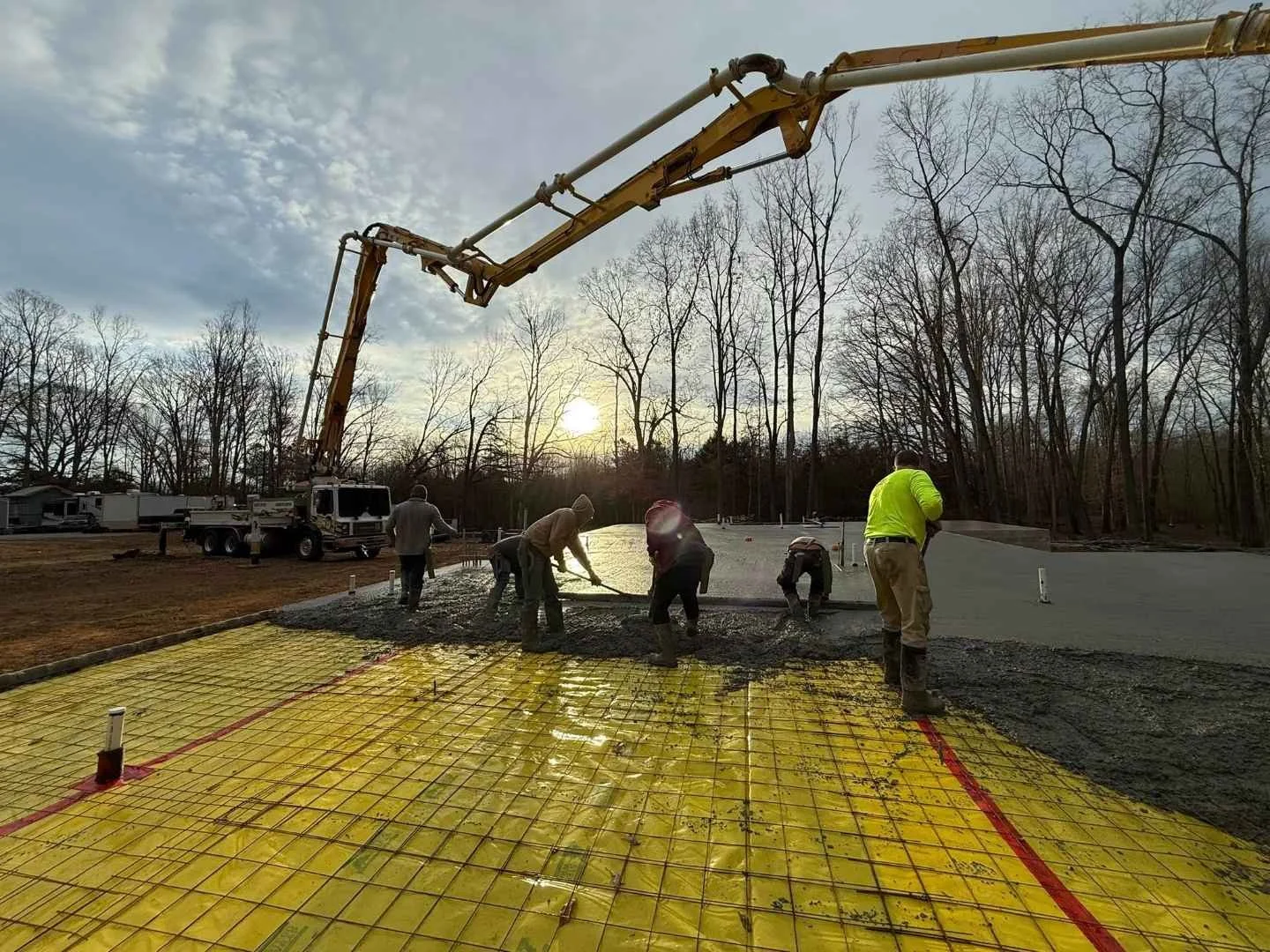 Crew pouring and finishing a concrete house slab foundation with rebar grid and vapor barrier