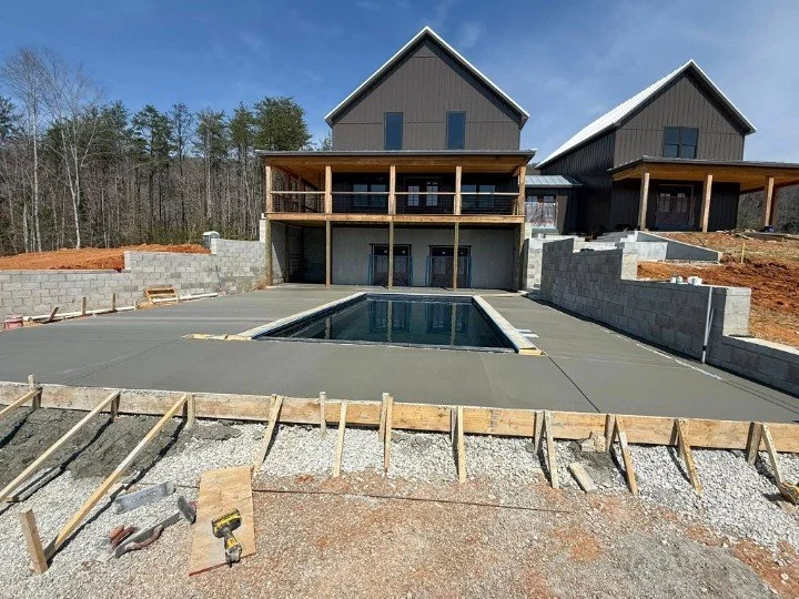 Freshly poured concrete pool deck installation in McMinnville, TN, with smooth finish, forming boards still in place, and block retaining walls surrounding the pool area.