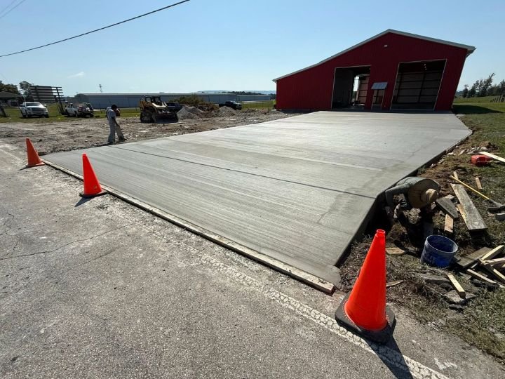 Freshly poured and finished concrete slab in front of a new volunteer fire hall with control joints and broom finish