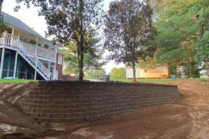 Backyard retaining wall built with concrete blocks near trees in Manchester, TN.