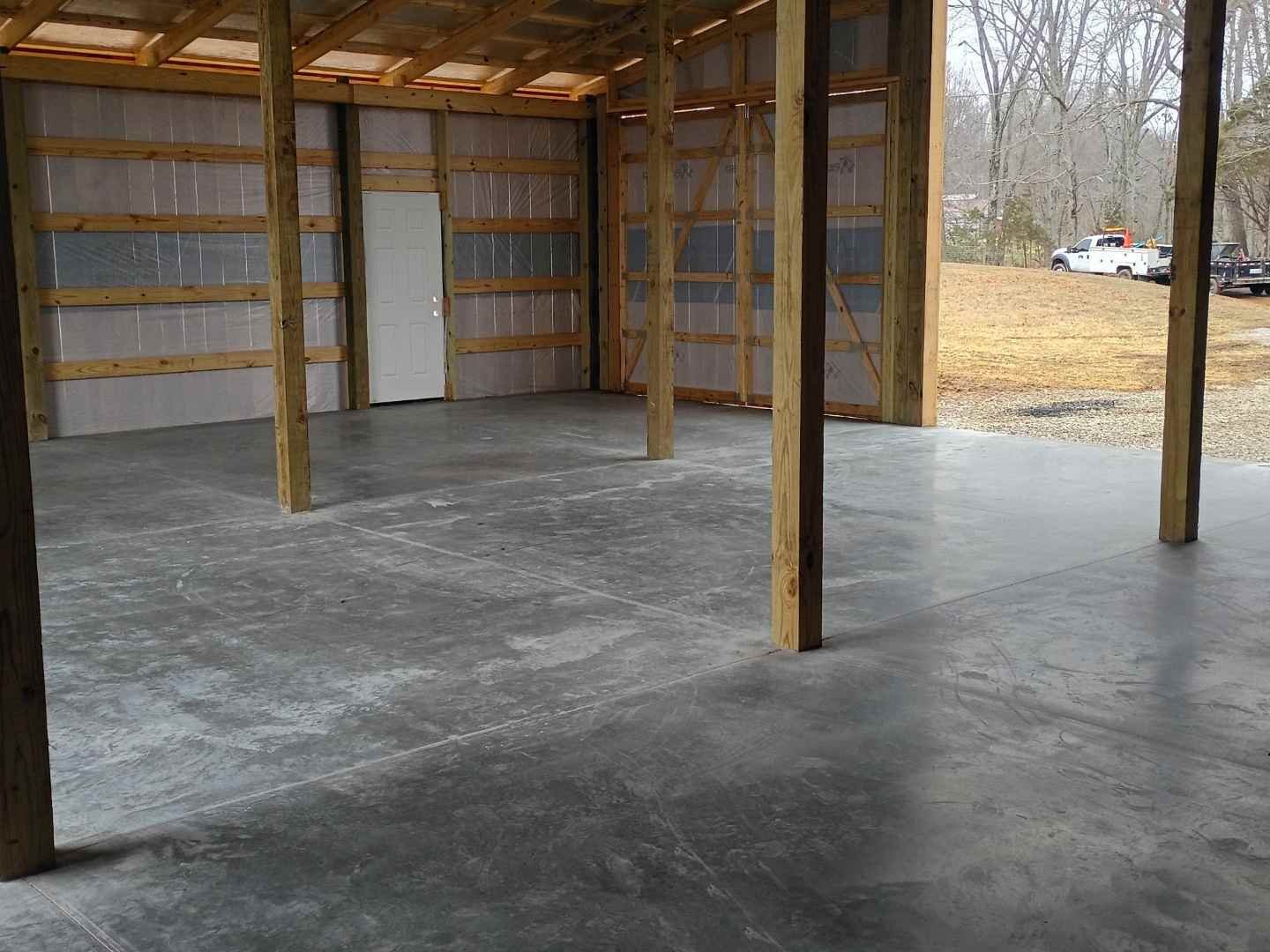 Finished concrete barn slab inside a pole barn with wood support posts