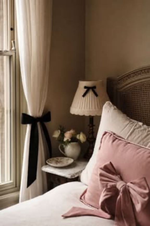Blush bedroom detail with black ribbon accents and layered textiles.