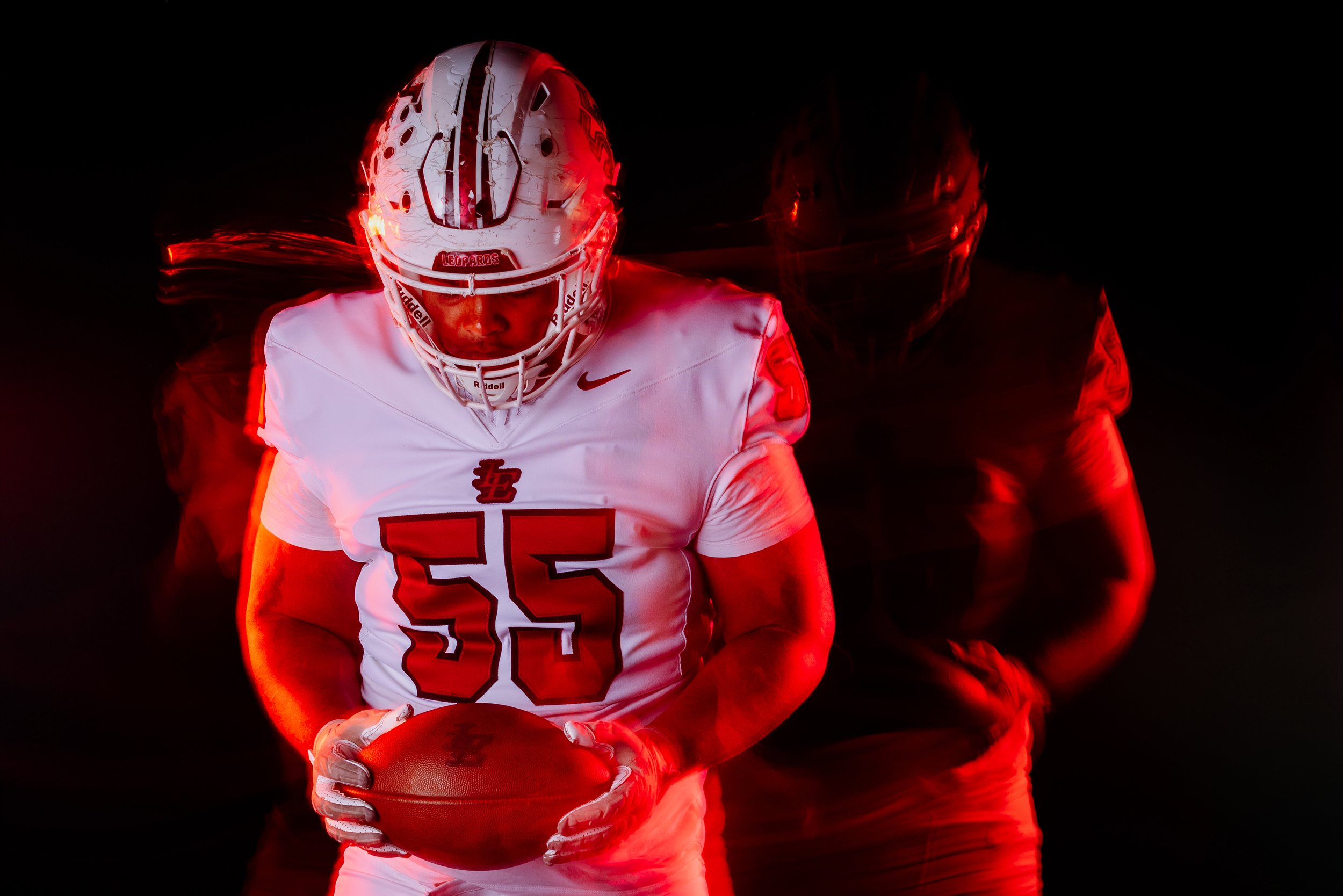 High school football player posing with dramatic lighting and smoke during media day