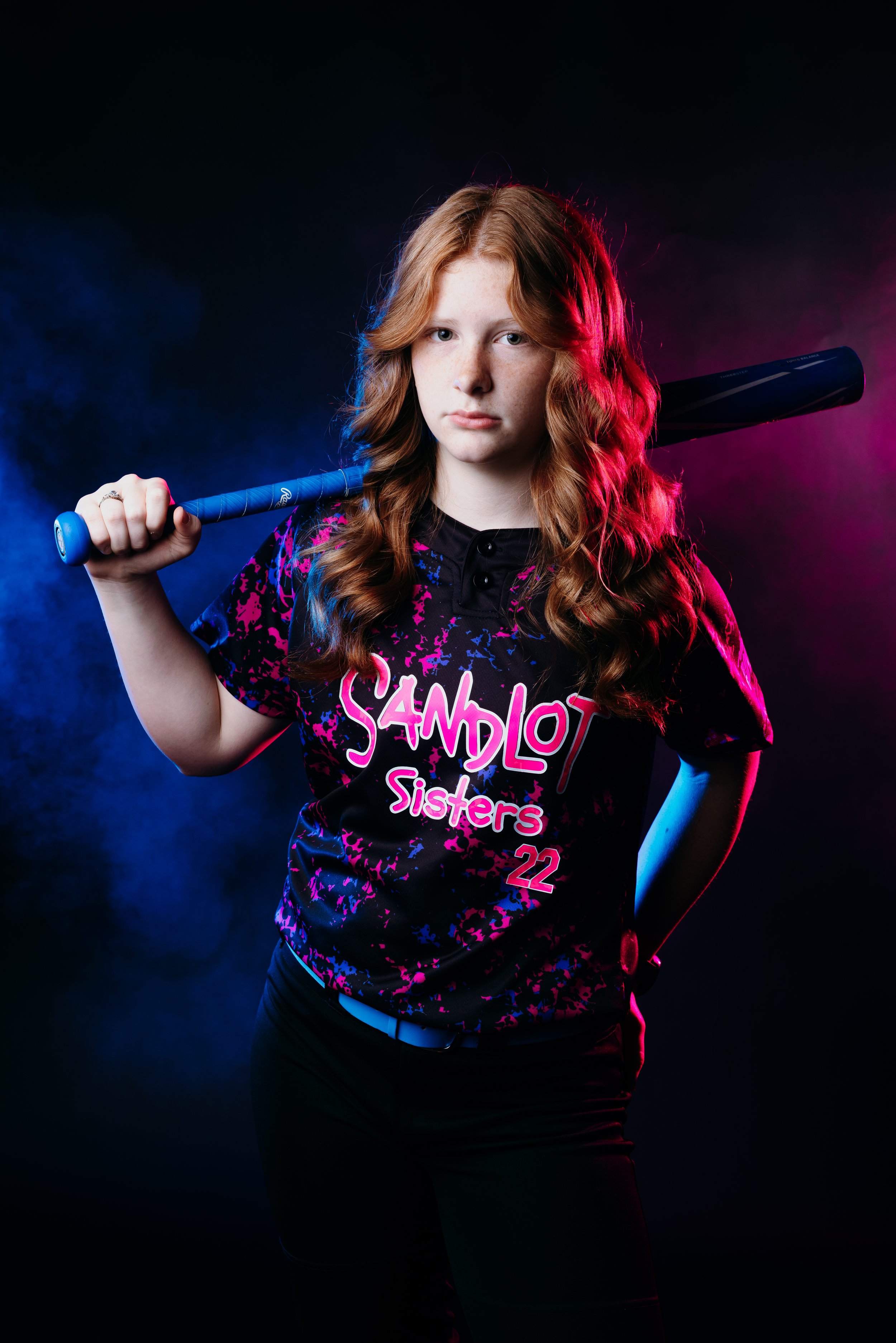 female softball player captured in a bold, high-impact sports session with fog backdrop