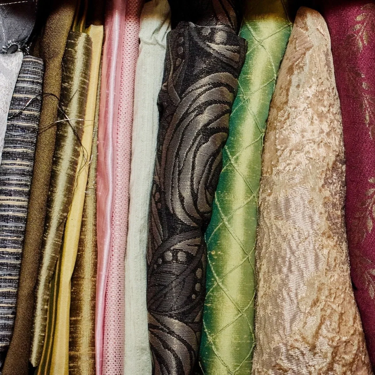 A variety of colorful and textured fabrics arranged vertically.