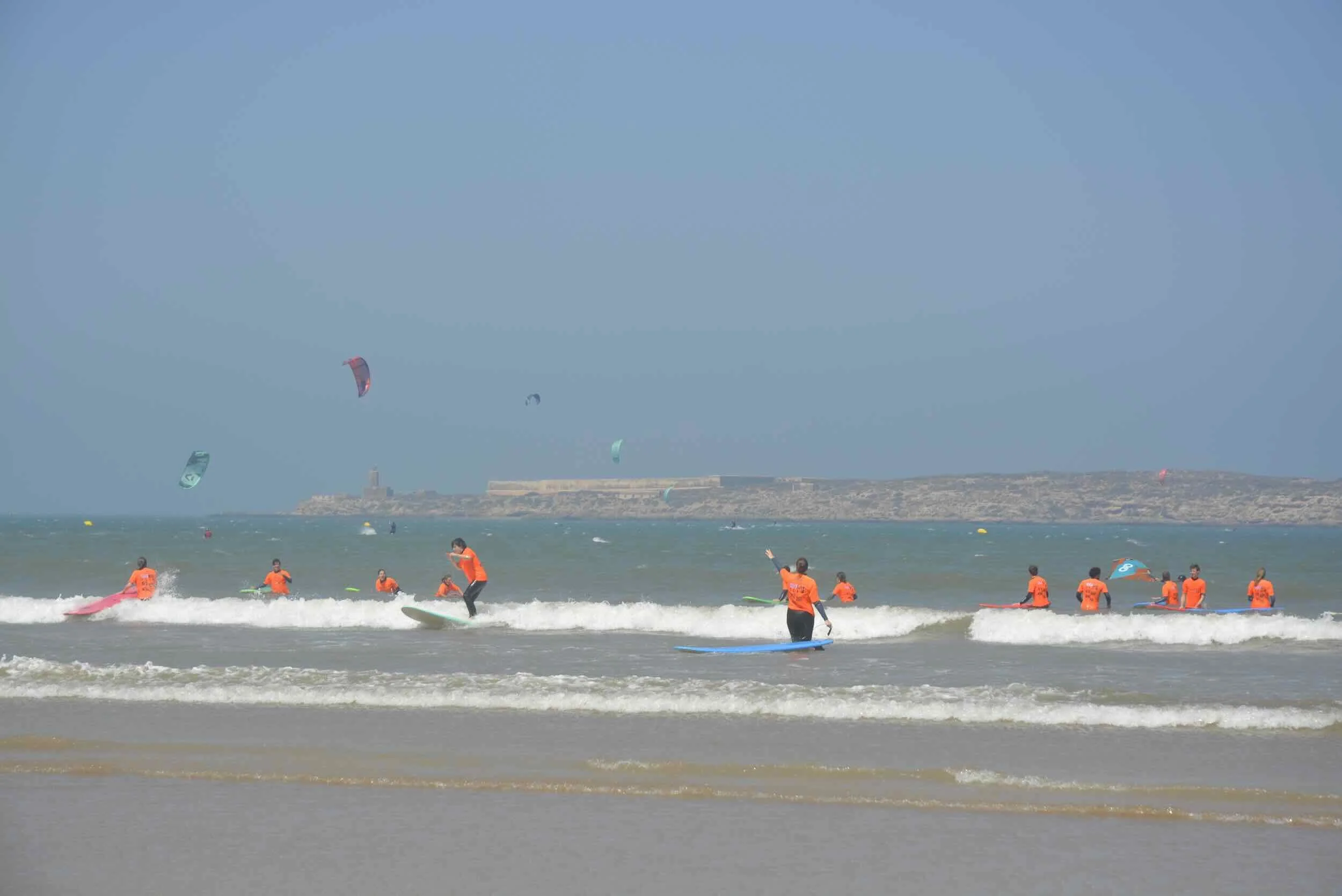 Team féminin en Team féminin de l'école de sport nautique Bluekite Essaouira, 'école de sport nautique Bluekite Essaouirale paddle surf et le kitesurf sur une plage ensoleillée, avec une mer calme et un ciel bleu.