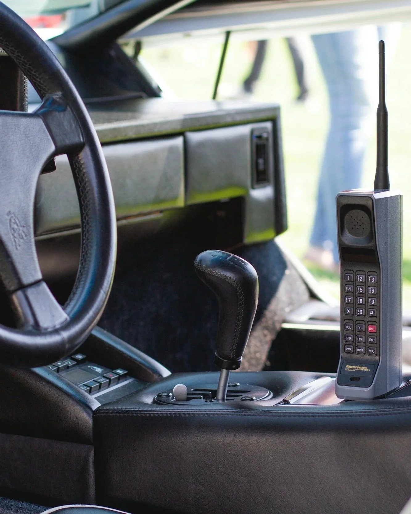 Inside the front cab of a vehicle, showing a steering wheel, gear shift, control buttons, and a two-way radio.