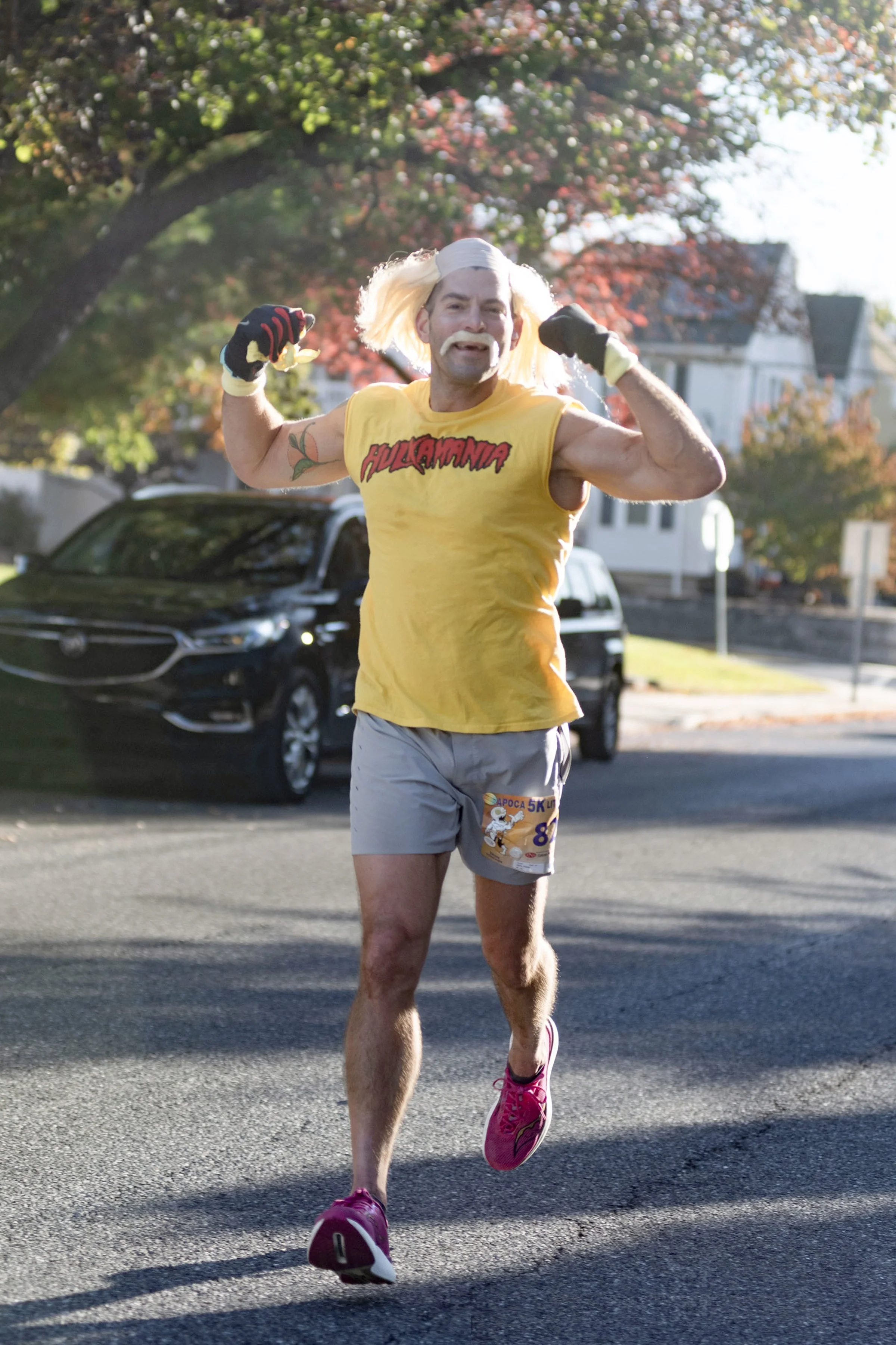 A man dressed in a humorous costume running in a race on a suburban street with houses and trees in the background.