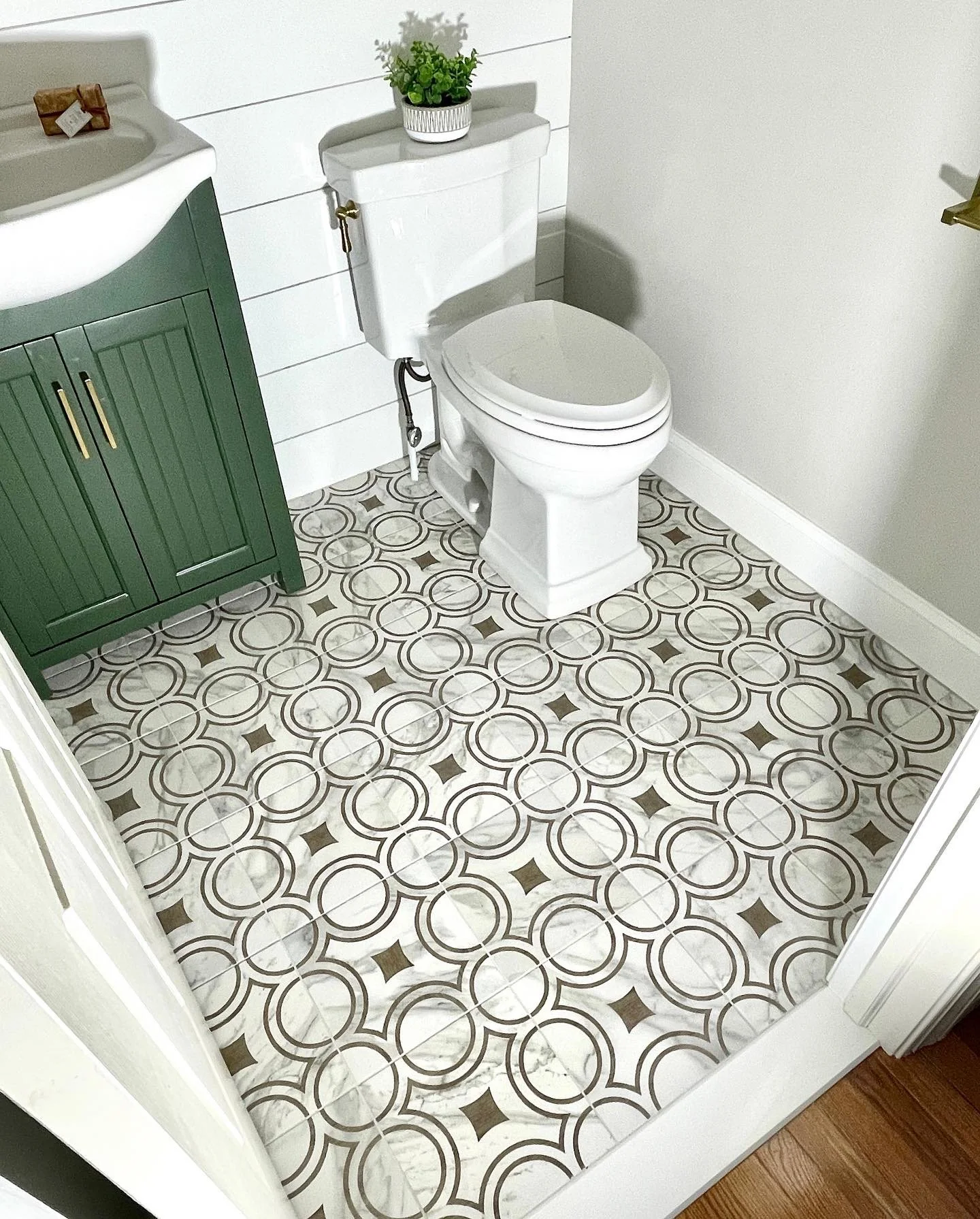 Powder room wood and marble pattern floor with a green vanity, designed and photographed by Sara Trotter / Chroma Maison Design.