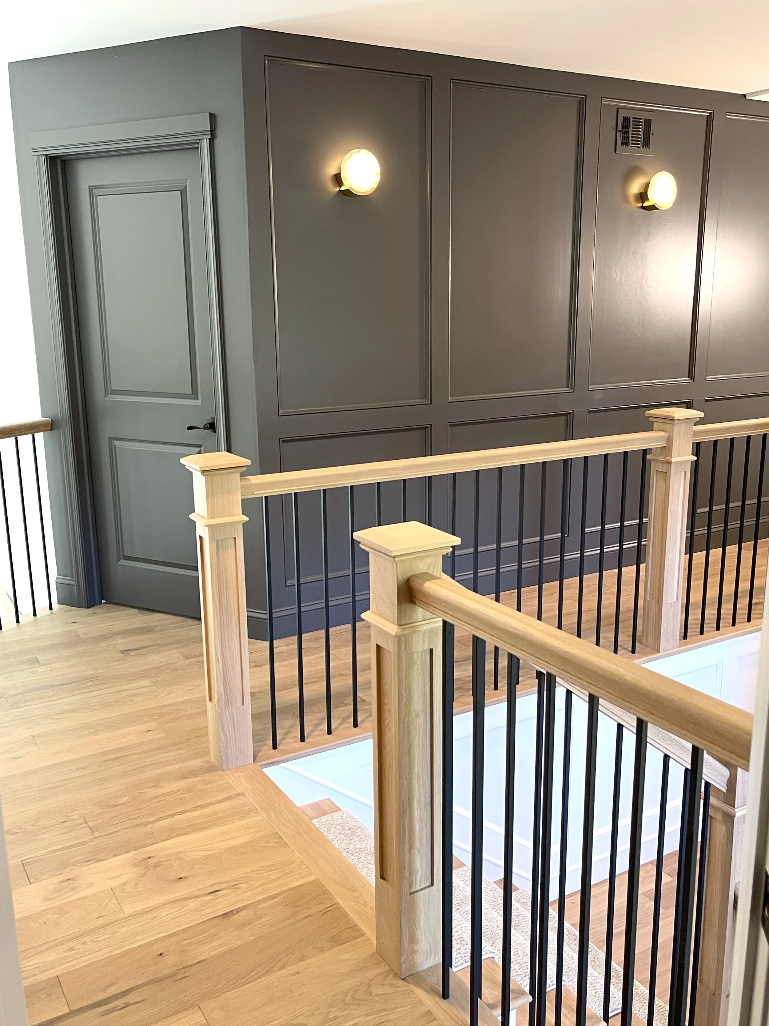 Second floor hall featuring alabaster brass sconces against Peppercorn painted wainscoting walls, designed and photographed by Sara Trotter / Chroma Maison Design.