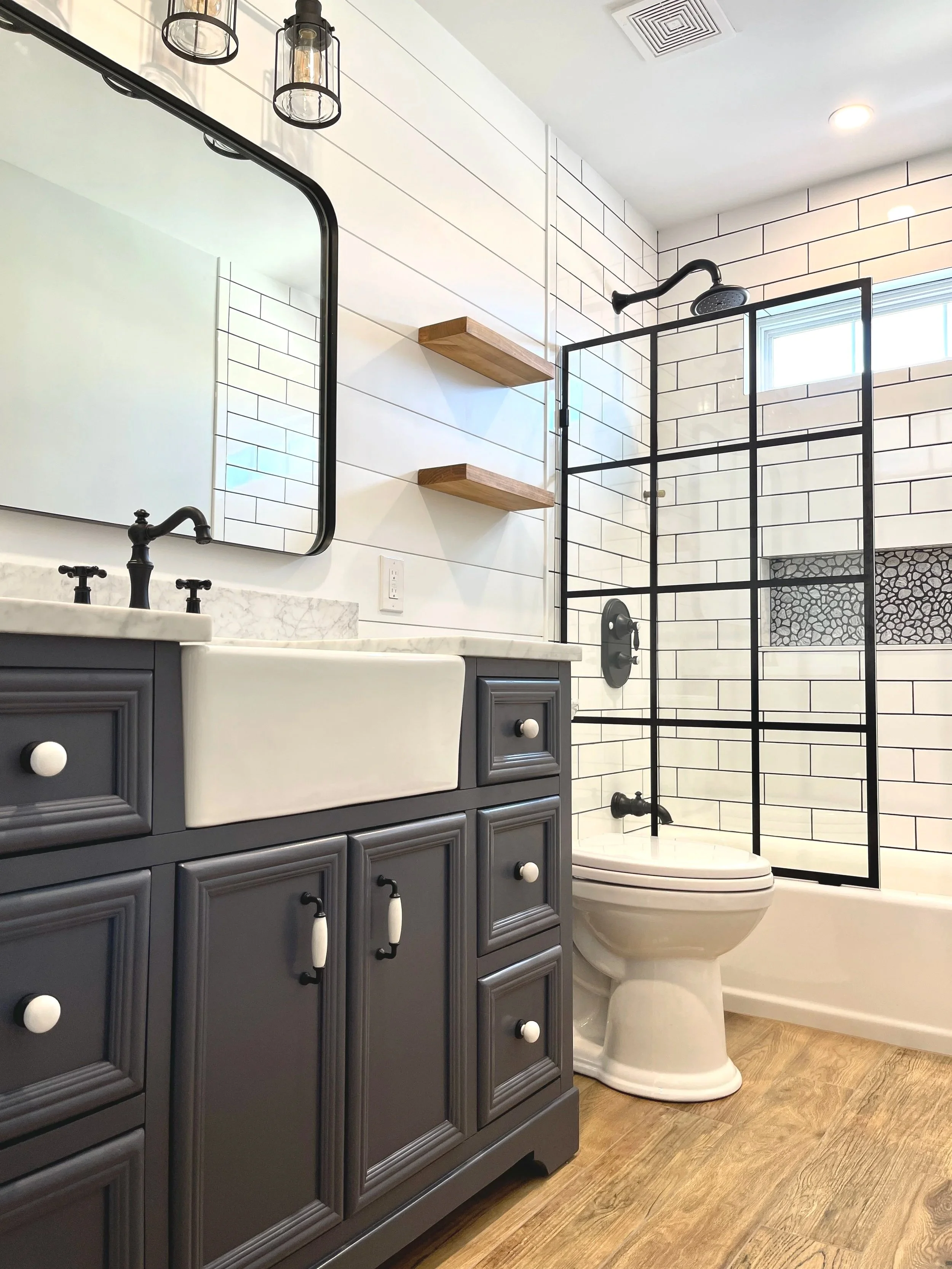 The perfect farmhouse bathroom featuring a vanity with an apron front sink, vintage plumbing, bead board, and window pane shower glass, designed and photographed by Sara Trotter / Chroma Maison Design.