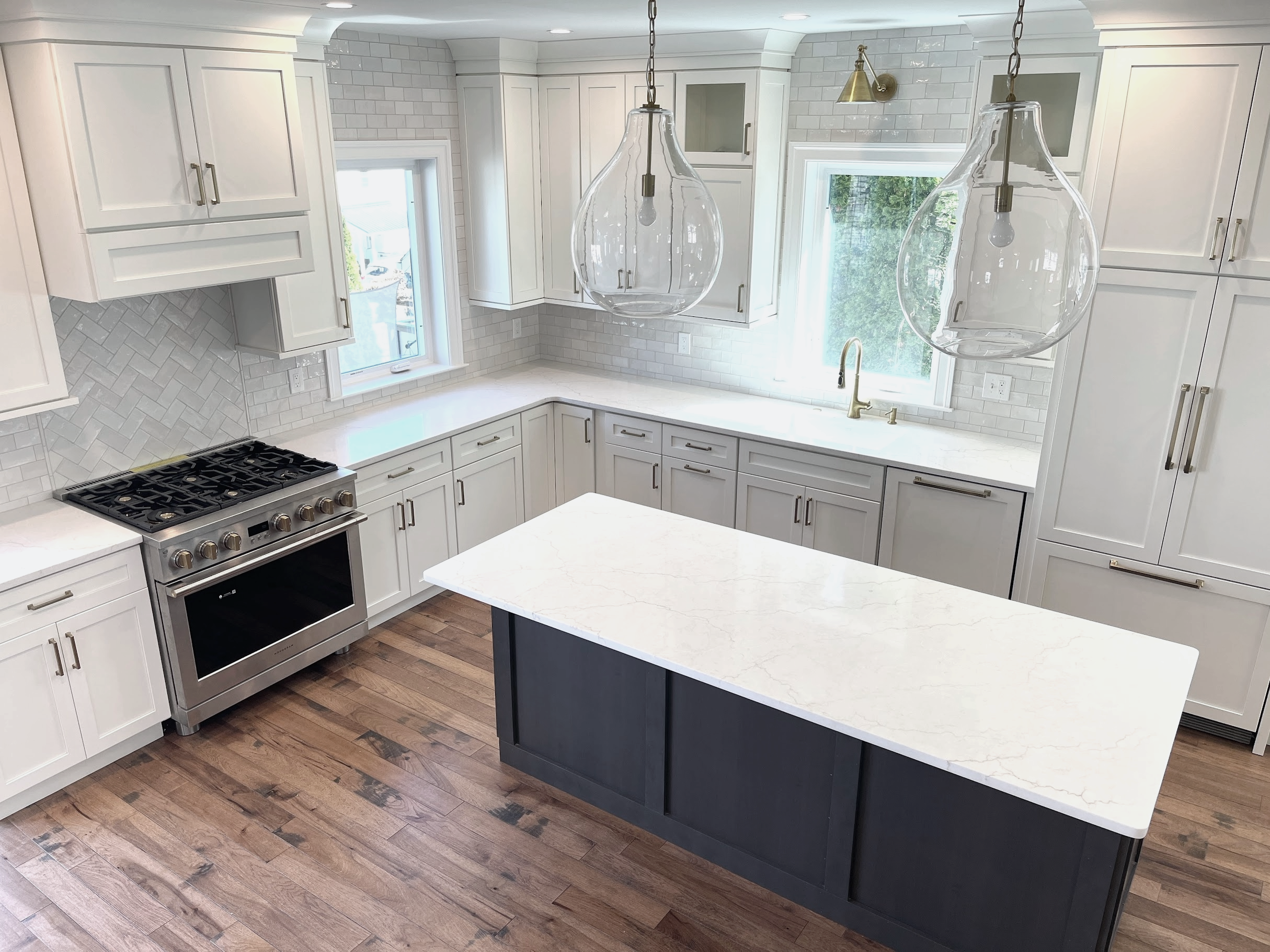 White kitchen with pewter wood island and wire brushed copper canyon hickory floor.  The oversized Visual Comfort pendants add drama to the scale of the room, designed and photographed by Sara Trotter / Chroma Maison Design.